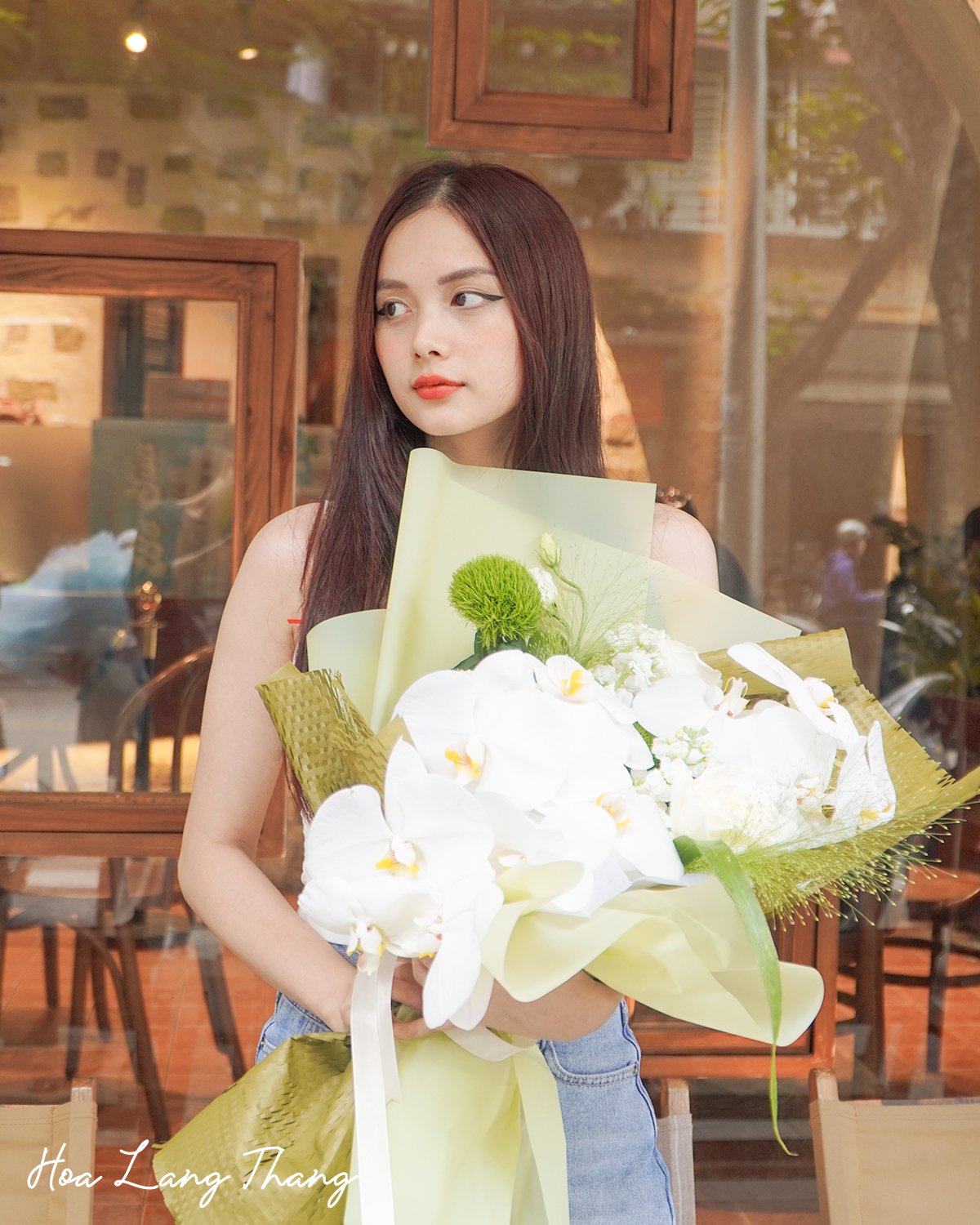 Cô gái cầm bó hoa lan hồ điệp trắng lớn, ngoài trời tươi sáng