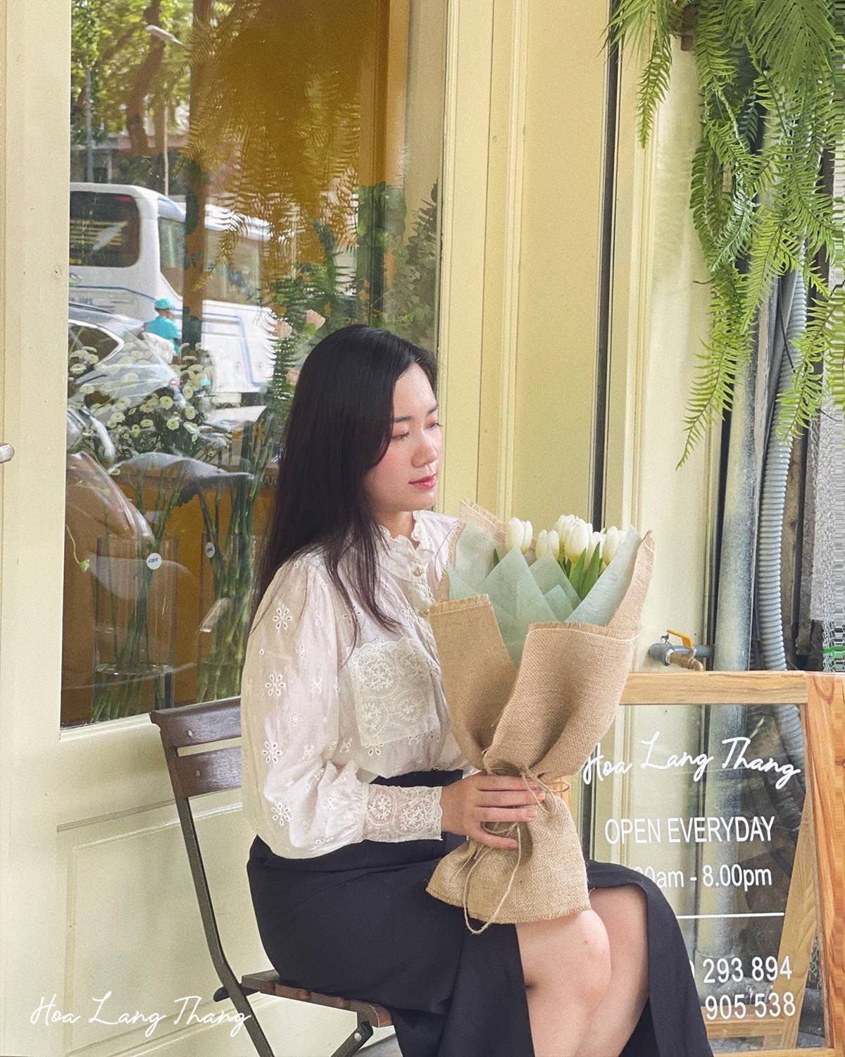 Cô gái cầm bó hoa sen trắng, chụp tại cửa hàng Hoa Lang Thang ở Hà Nội