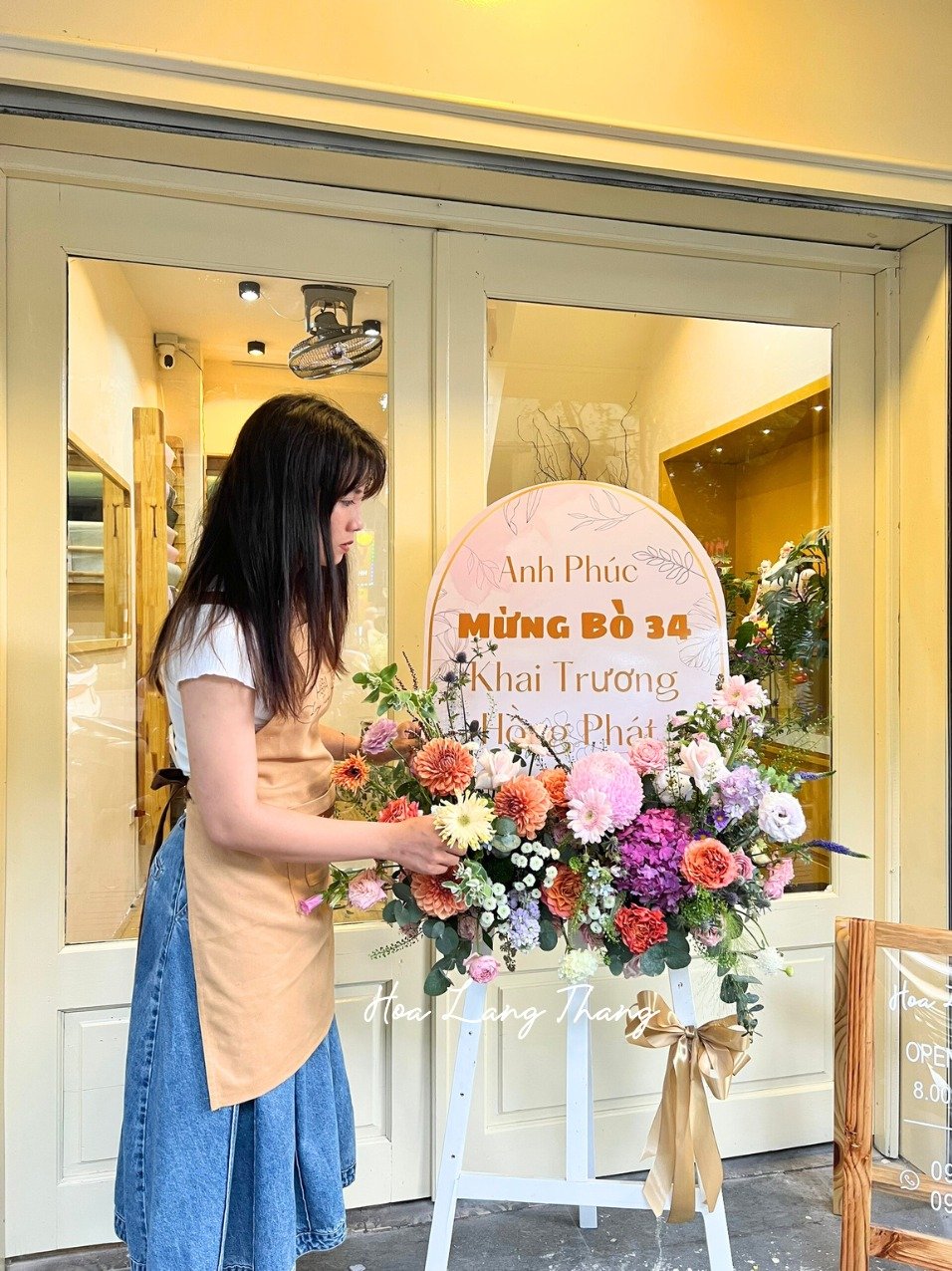 Người phụ nữ trang trí hoa chúc mừng khai trương với hoa hồng, cát tường, và baby