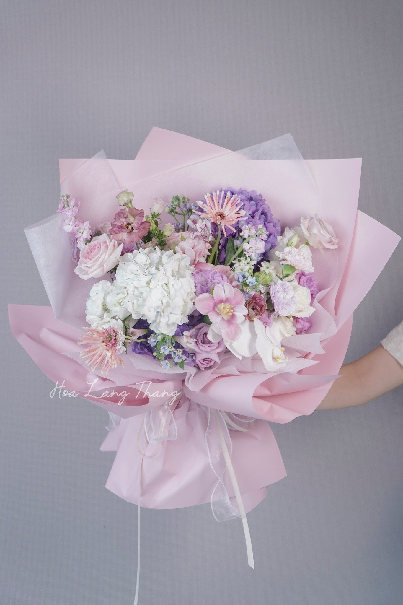 Bó hoa gồm hoa hồng, lan hồ điệp, thủy tiên màu sắc pastel, kiểu cắm hiện đại