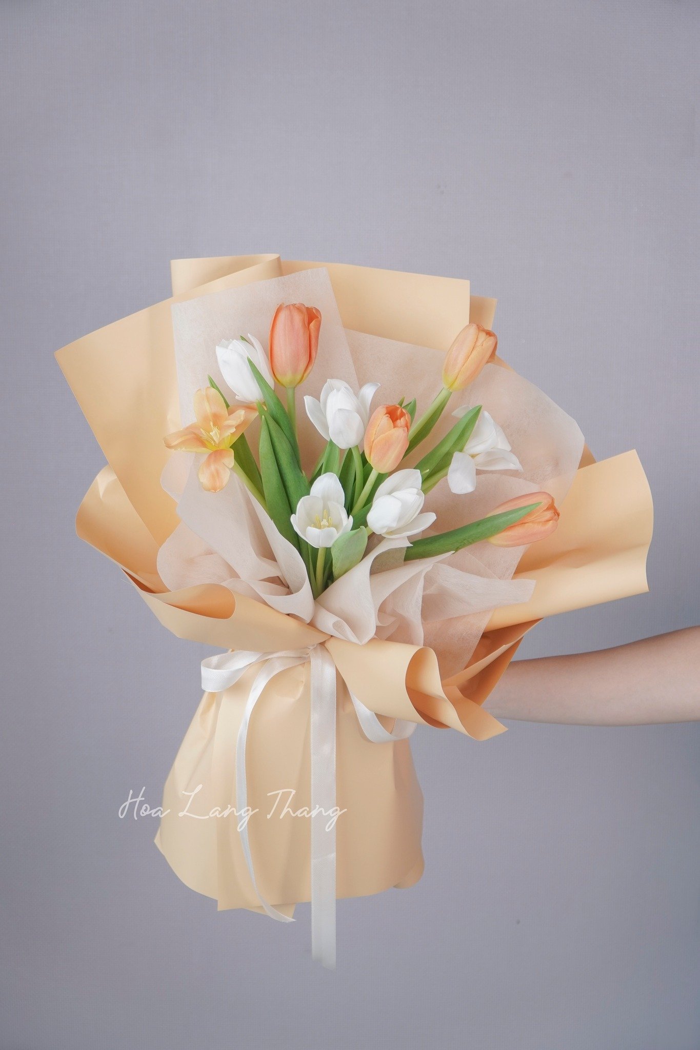 Bó hoa tươi gồm tulip cam, trắng và lan hồ điệp, trang trí đẹp mắt