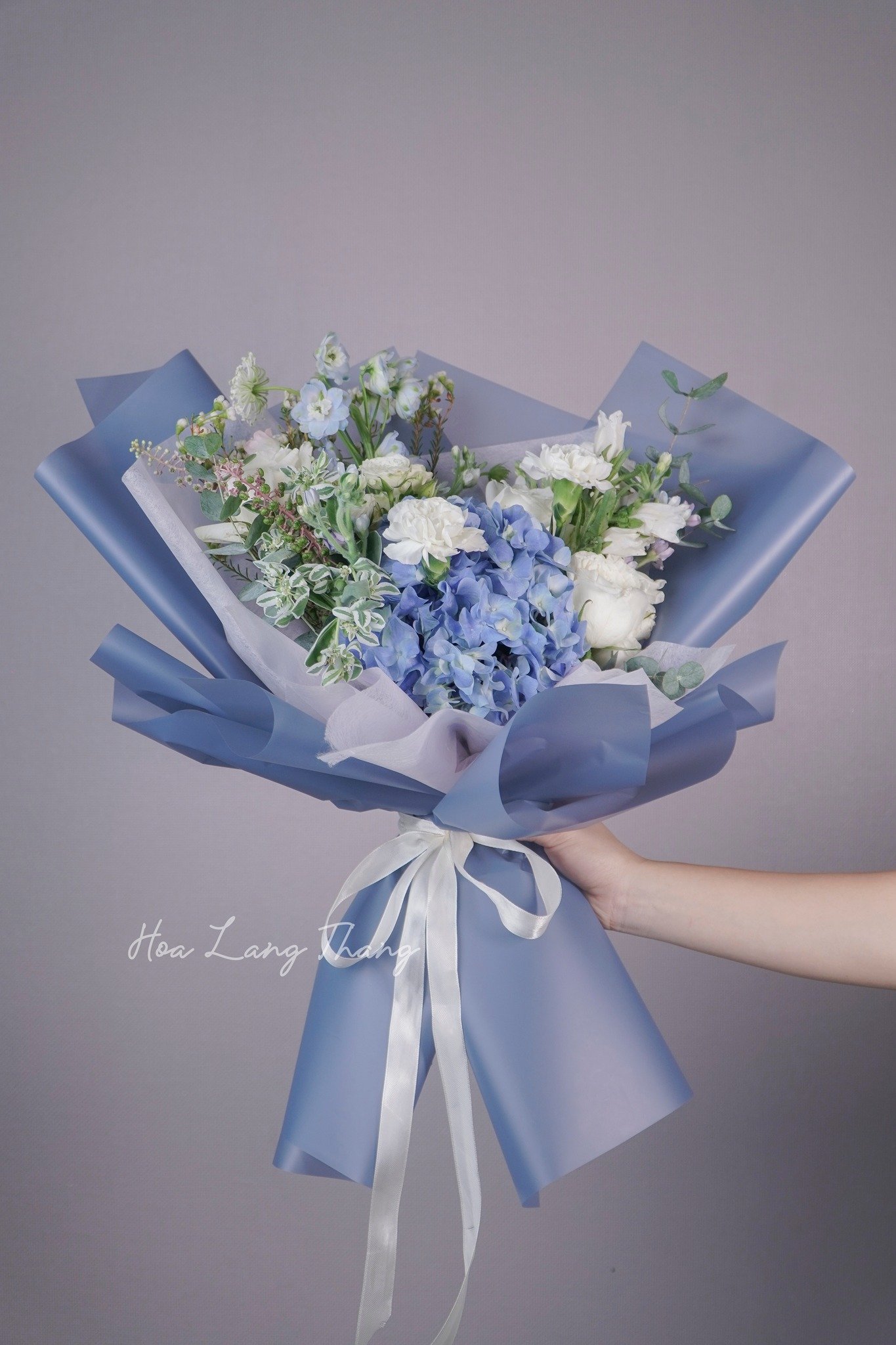 Bó hoa với sắc xanh nhẹ nhàng, gồm hoa cẩm tú cầu, lan hồ điệp và hoa baby, kiểu cắm đẹp mắt