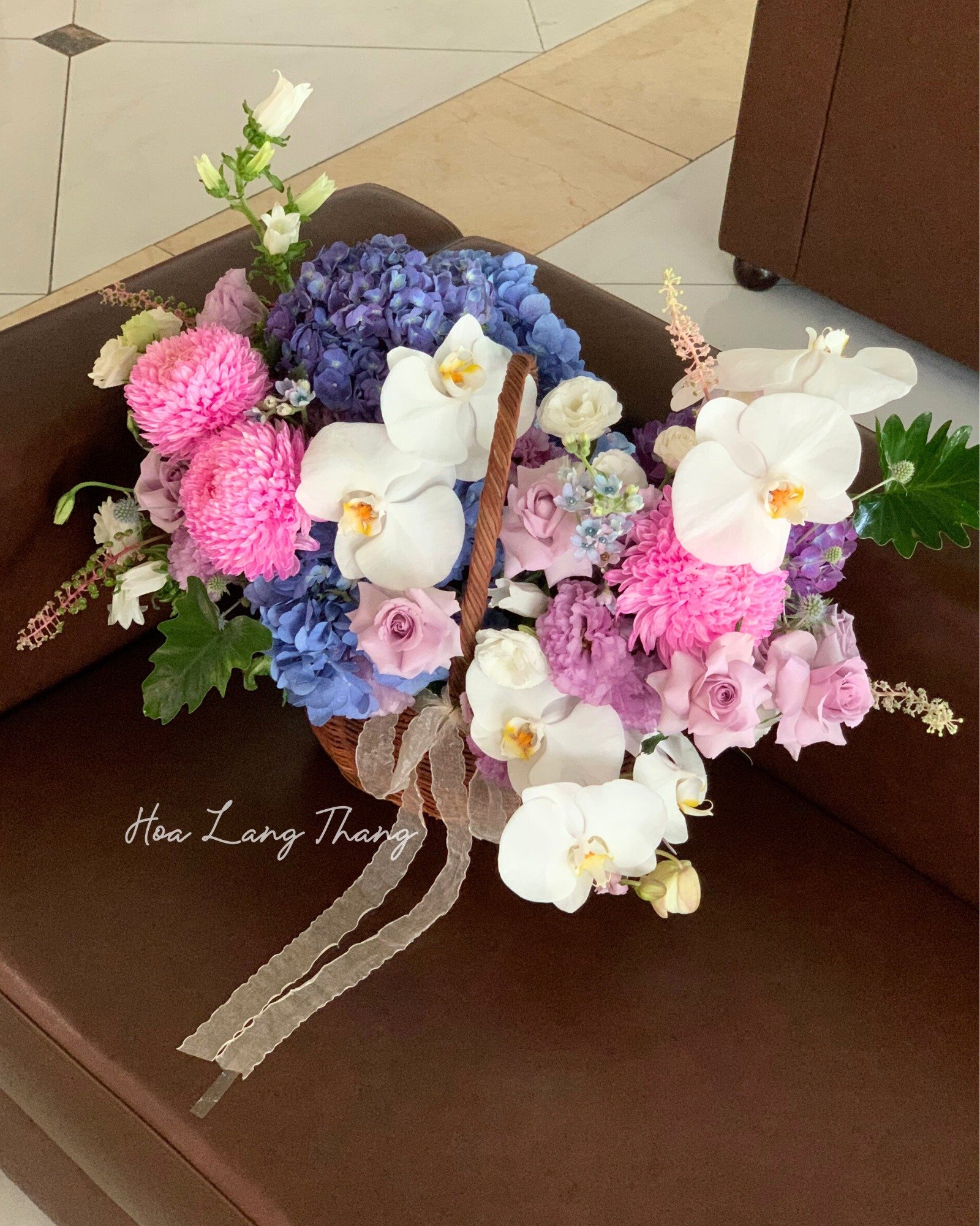 Giỏ hoa đẹp gồm hoa lan hồ điệp, cúc, hoa hồng và màu pastel nhẹ nhàng