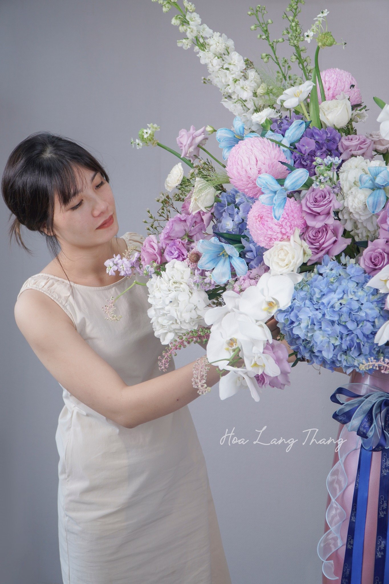 Cô gái đang cắm hoa gồm cúc, hồng, lan hồ điệp đẹp mắt