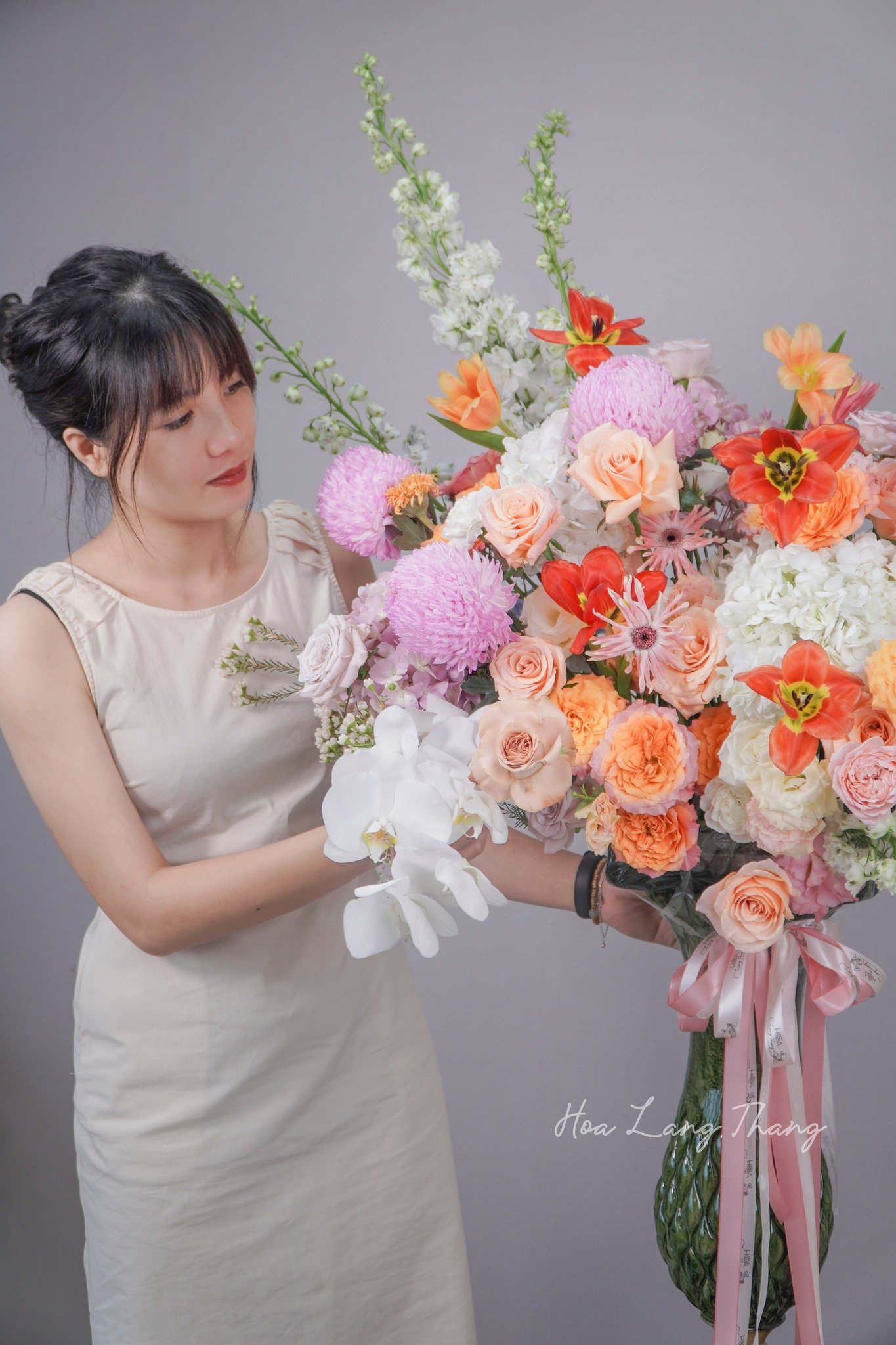 Cô gái cầm bó hoa lớn với đầy đủ hoa hồng, cúc, lan hồ điệp, kiểu cắm sang trọng
