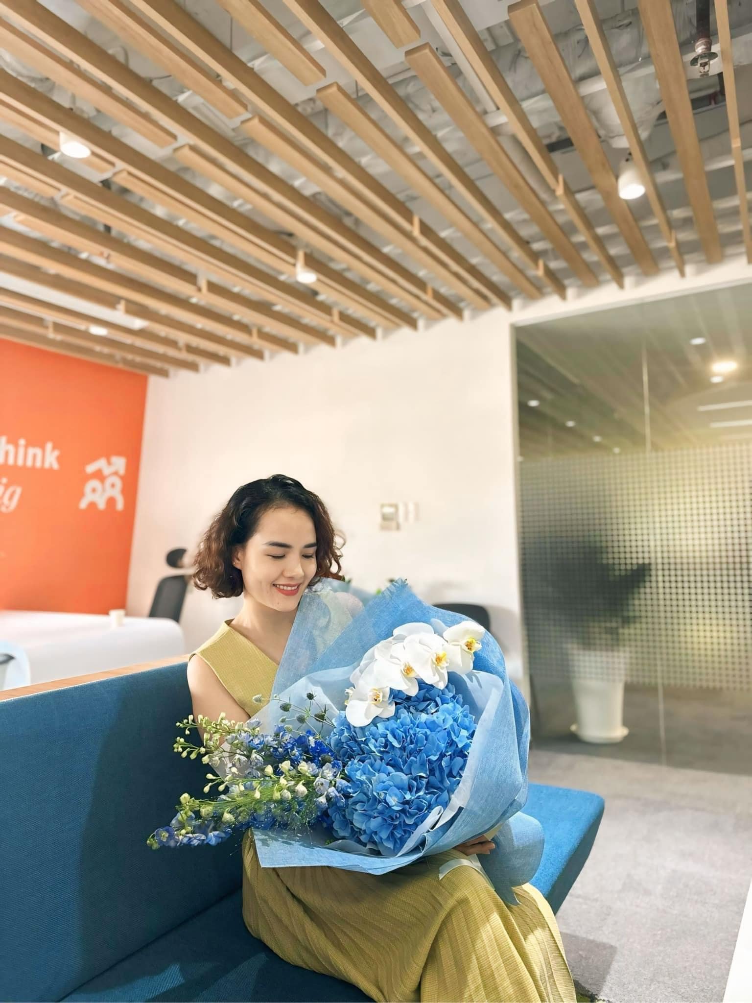 Người phụ nữ vui vẻ cầm bó hoa xanh, cắm kết hợp với <a href=