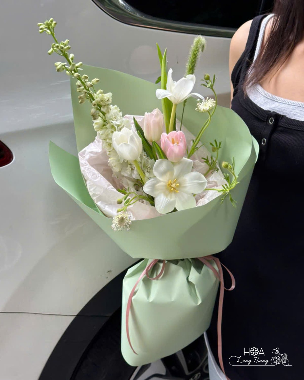 🍀 Bó hoa trẻ trung với sắc trắng tinh khôi và hồng nhẹ nhàng từ hoa tulip, nổi bật trên nền giấy xanh bơ tươi mát, mang lại c