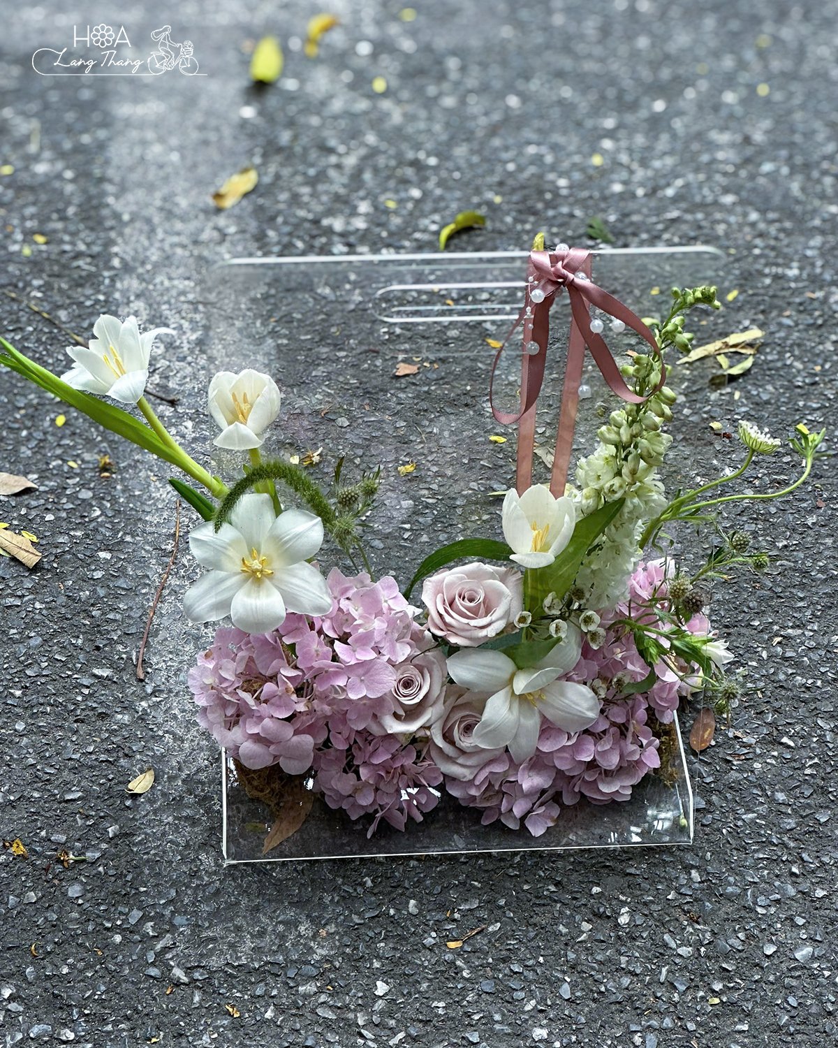 Bình hoa đặt trên nền đất với hoa hồng, lan, và tulip, kiểu cắm hiện đại