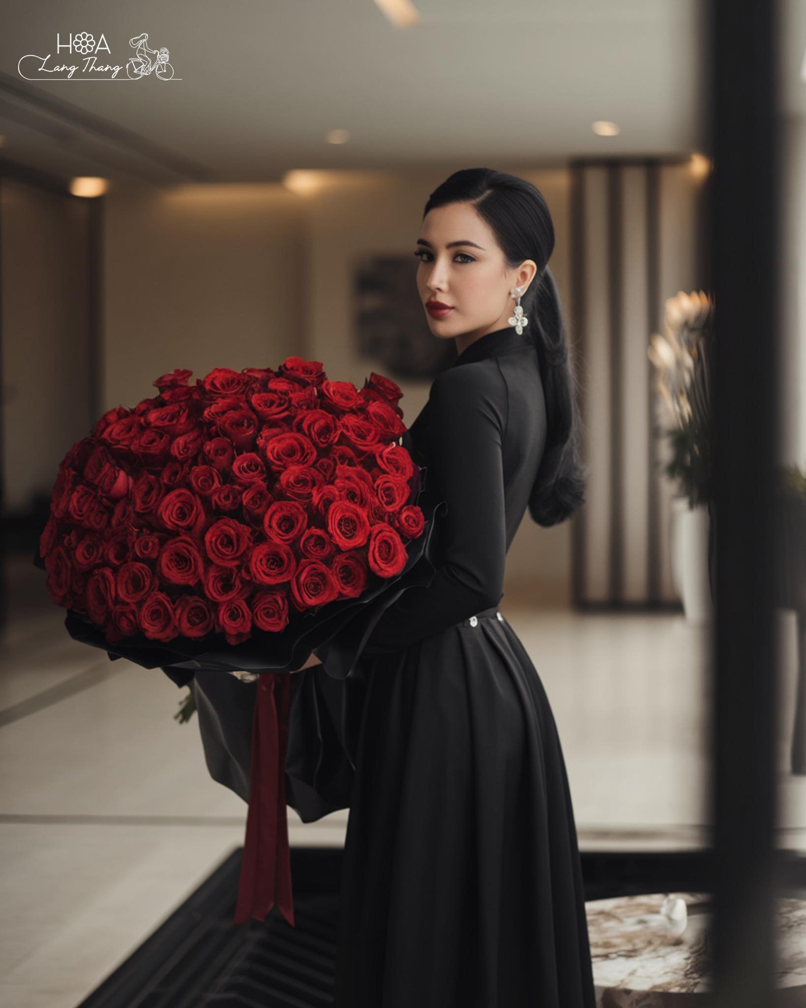 Người phụ nữ trong áo dài cầm bó hoa hồng đỏ lớn, trang nhã và thanh lịch