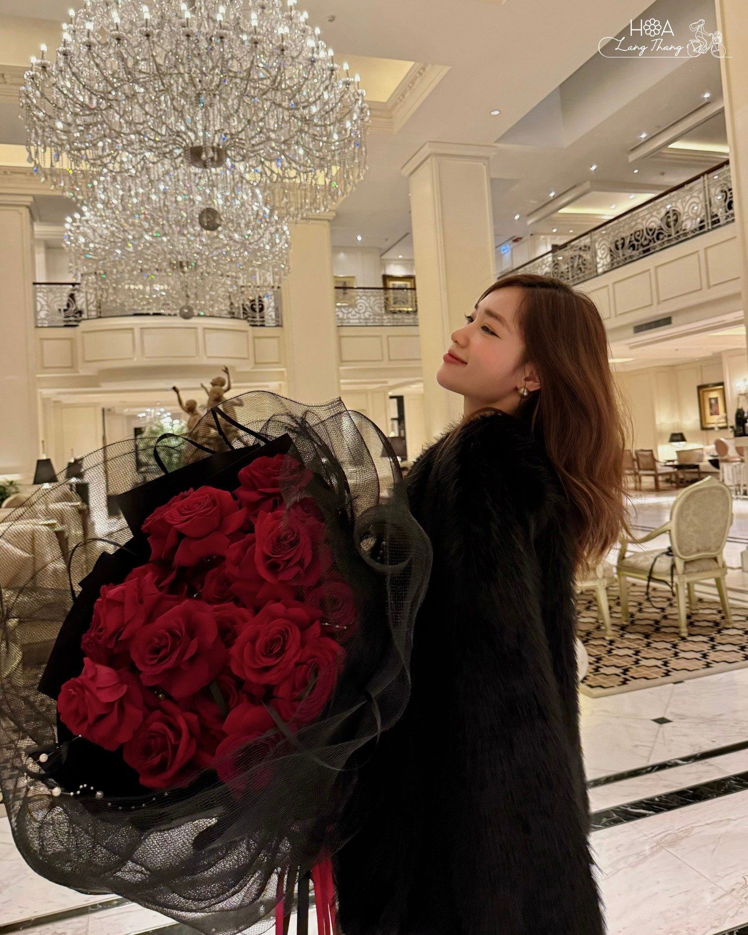 Cô gái xinh đẹp cầm bó hoa hồng đỏ tại sảnh sang trọng