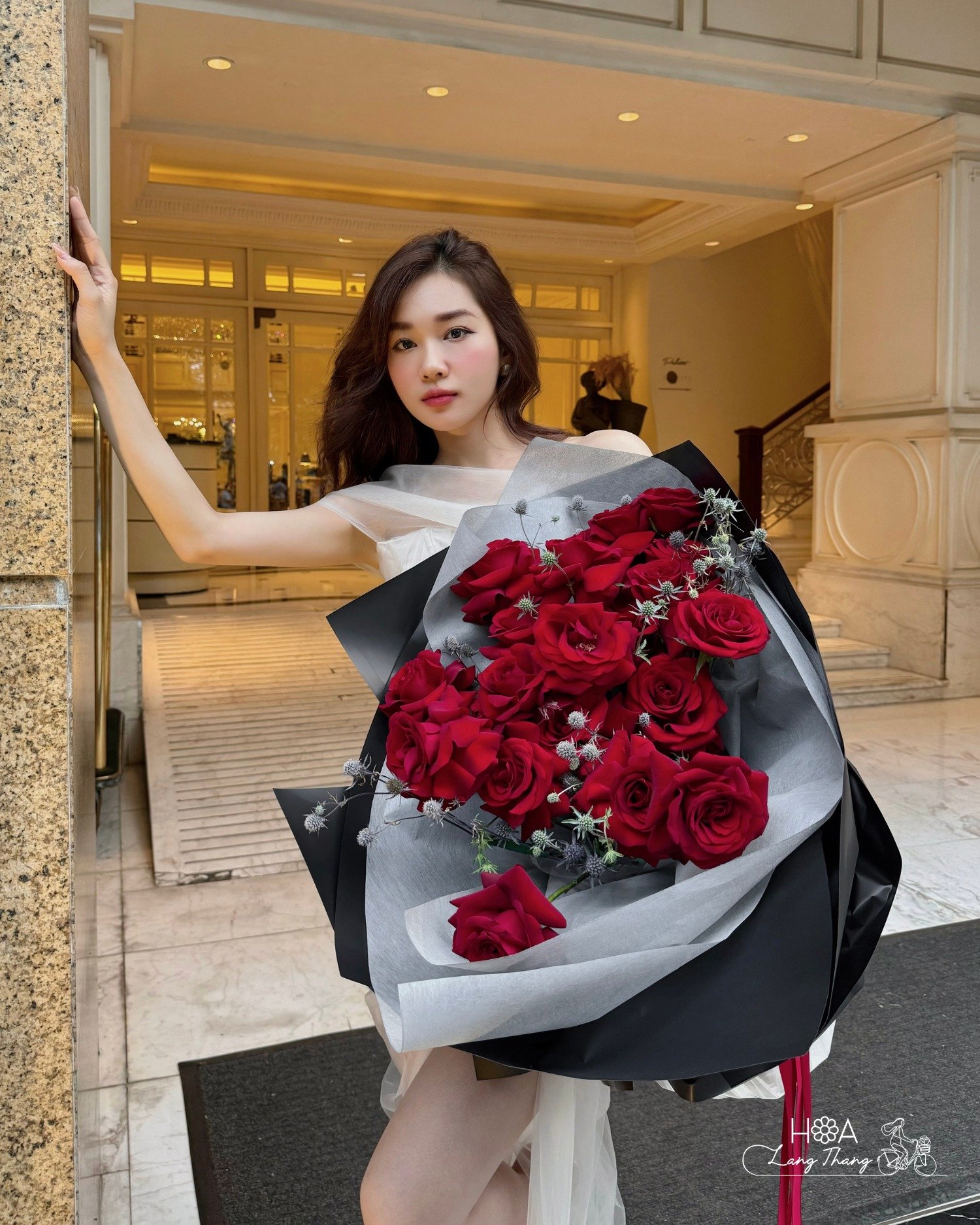 Cô gái xinh đẹp cầm bó hoa hồng đỏ sang trọng và quyến rũ