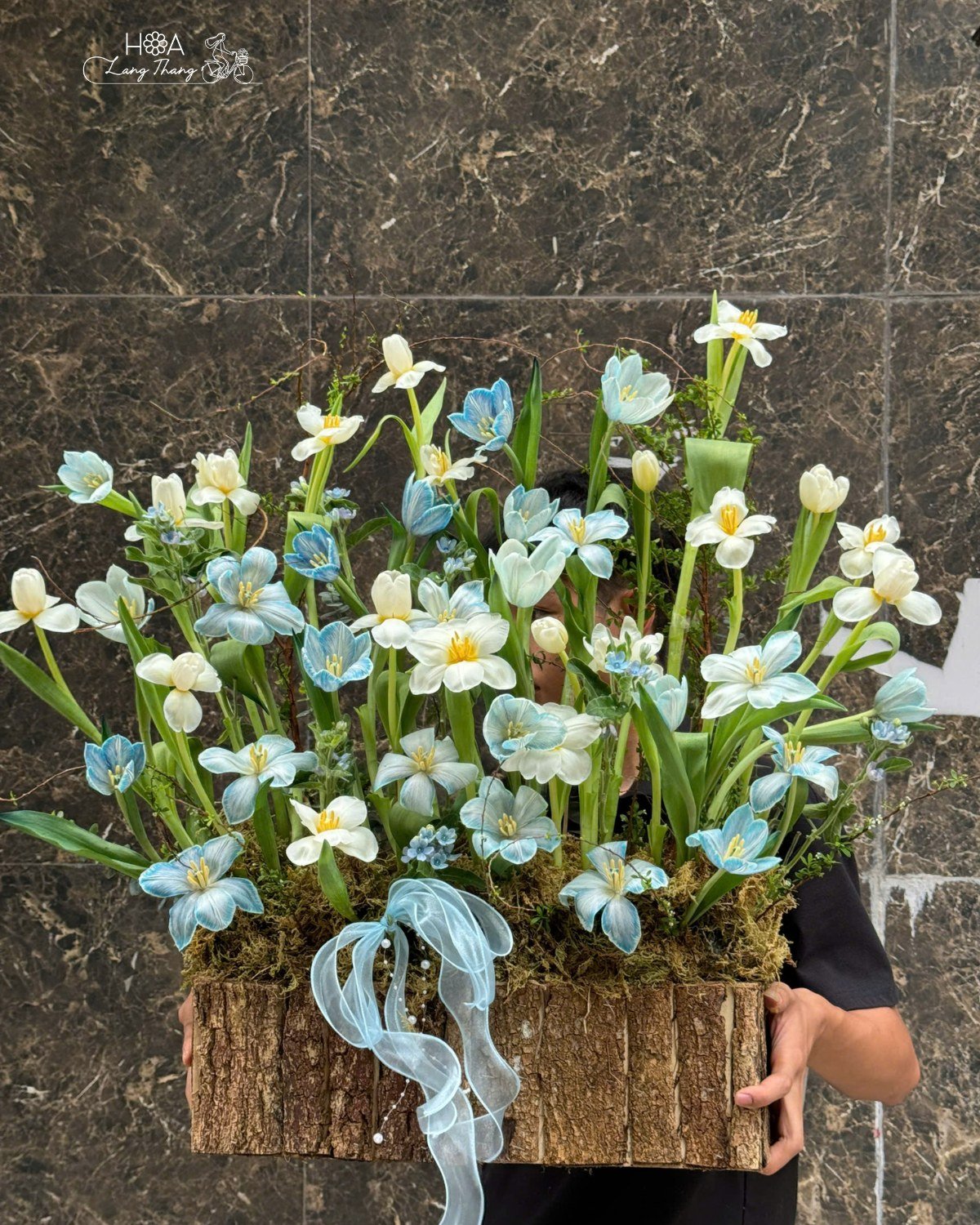 Một bình hoa cắm nghệ thuật với hoa tulip và lan hồ điệp xanh trắng