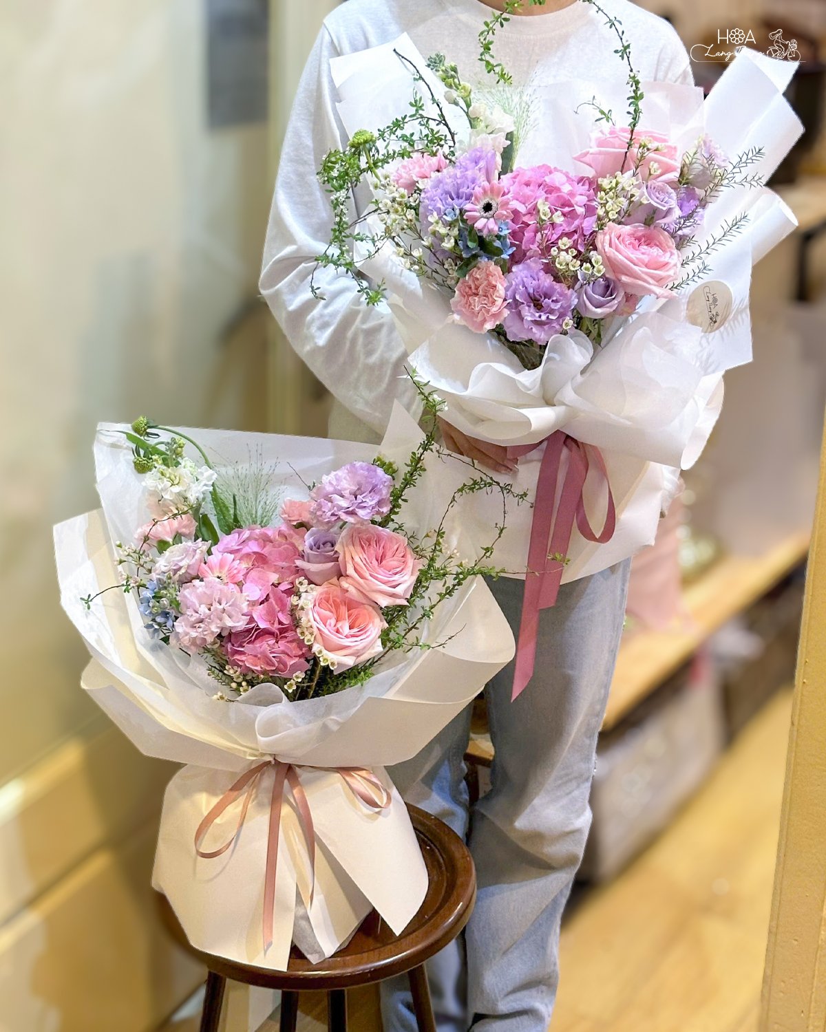 Hai bó hoa rực rỡ với hoa hồng và cẩm chướng, kiểu cắm sang trọng