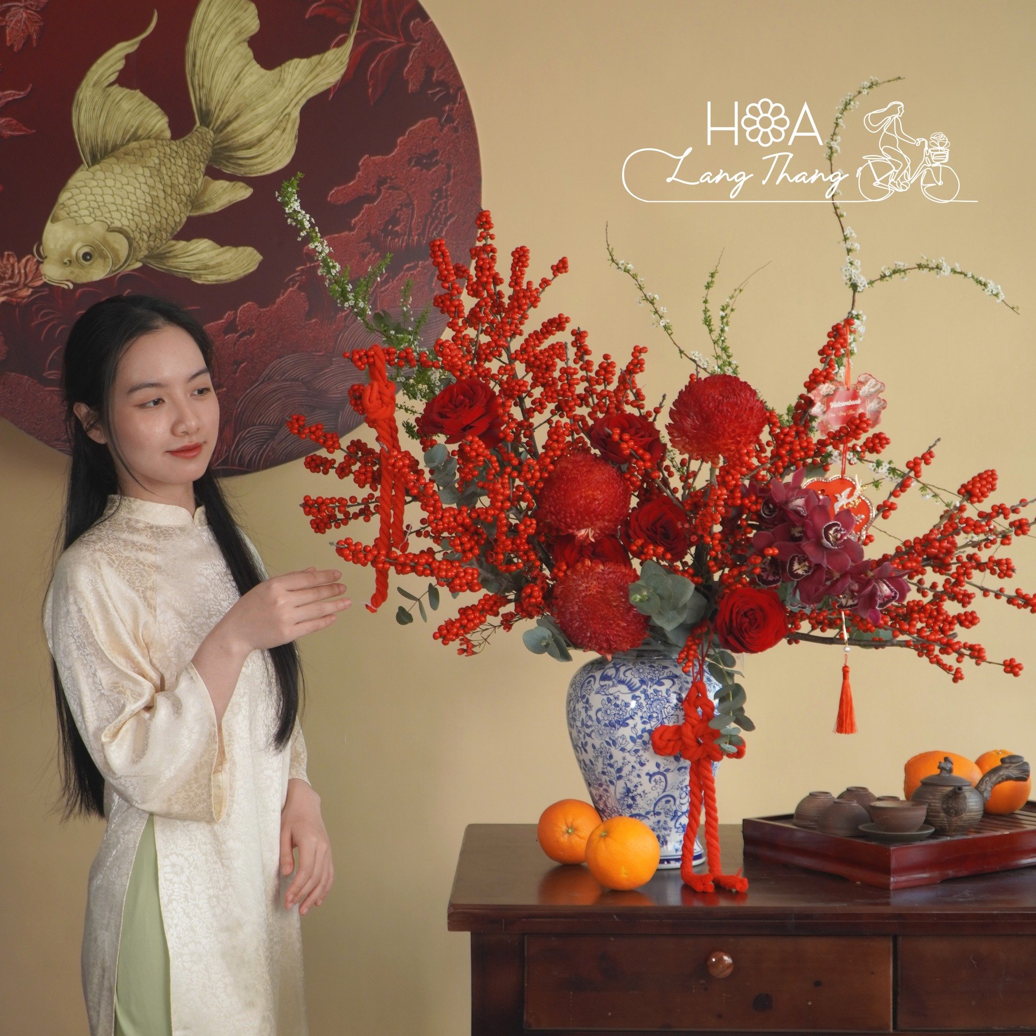 Bình hoa tươi với màu đỏ nổi bật, chứa hoa hồng, cúc và cam tú cầu, kiểu cắm nghệ thuật