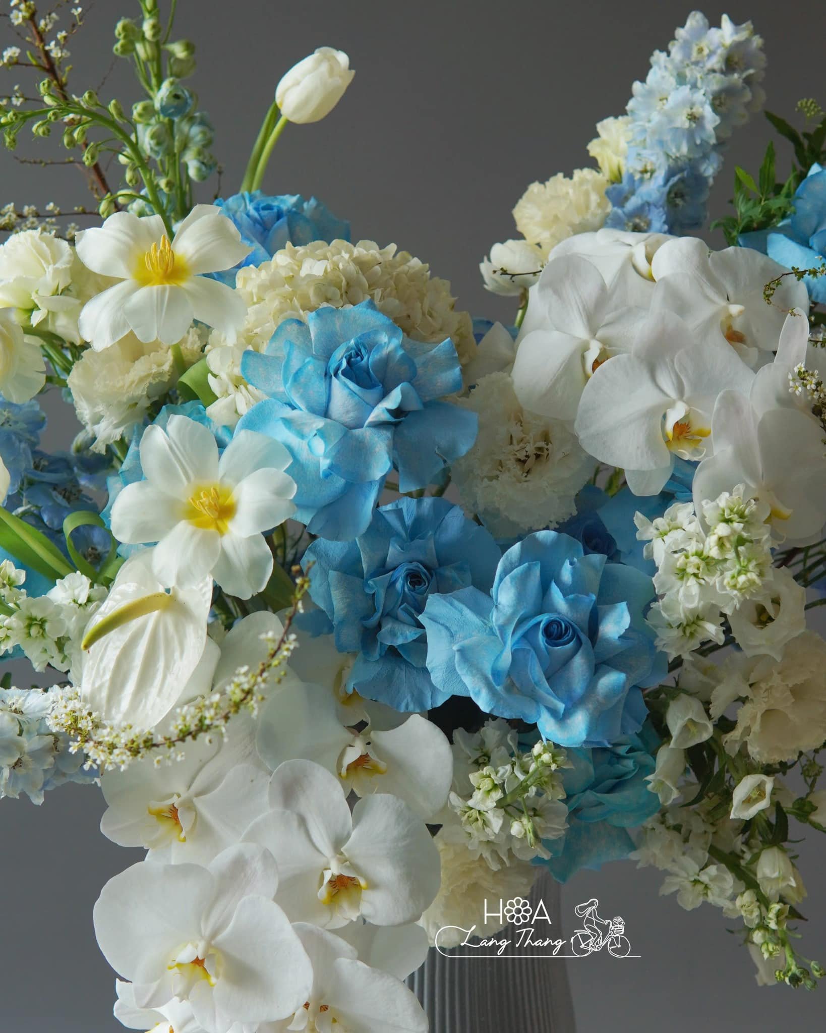 Bouquet rực rỡ xanh dương và trắng với hoa hồng, lan hồ điệp, thuyền tiên