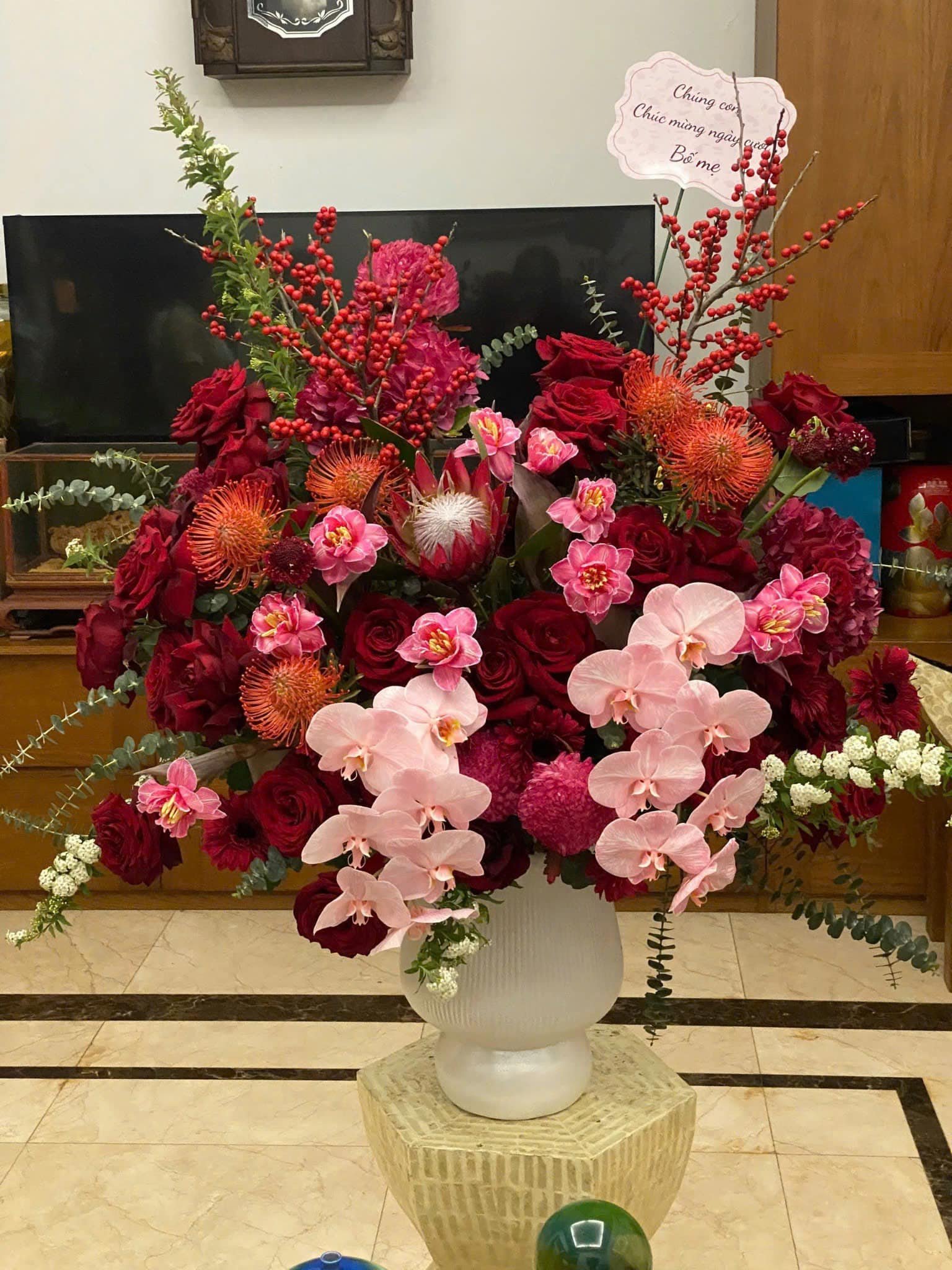Bình hoa lớn gồm hồng đỏ, lan hồ điệp, và cúc tạo điểm nhấn rực rỡ