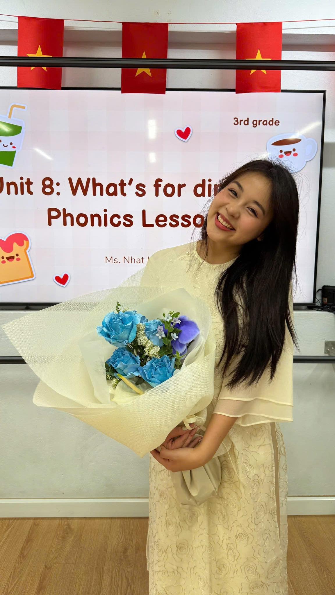 Cô gái cầm bó hoa với hoa hồng và lan hồ điệp, bên bảng lớp học