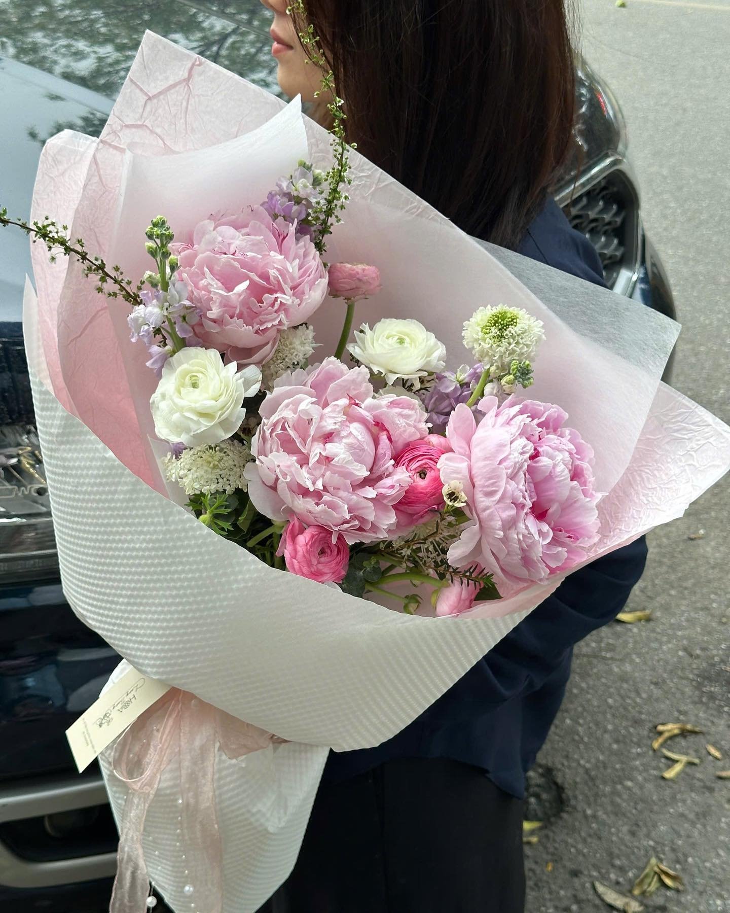 Bó hoa với nhiều hoa hồng và peony màu hồng, điểm xuyết hoa trắng, kiểu cắm tự nhiên