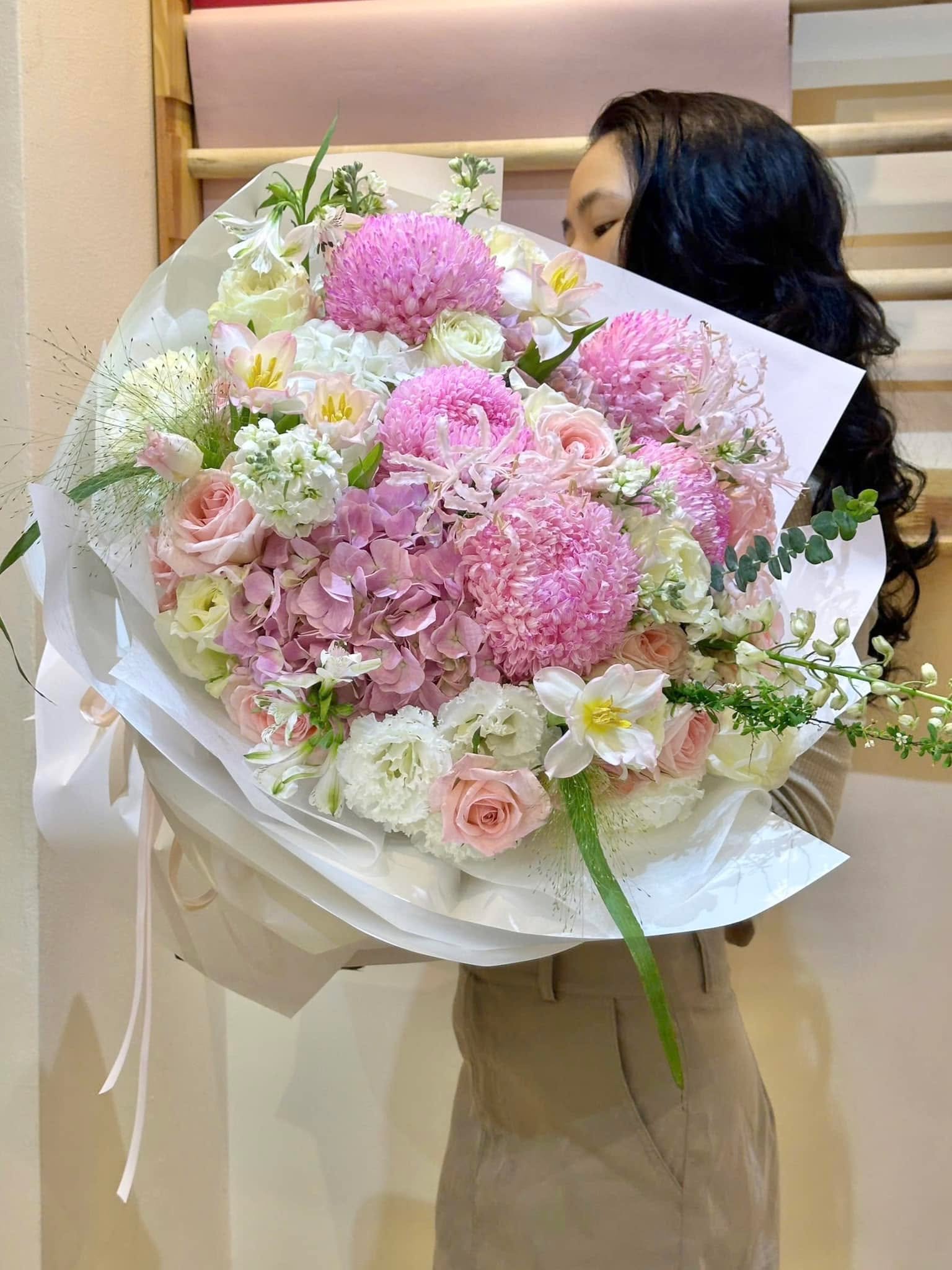 Bó hoa lớn đầy màu sắc gồm hồng, cúc, và lan, kiểu cắm bông nổi bật