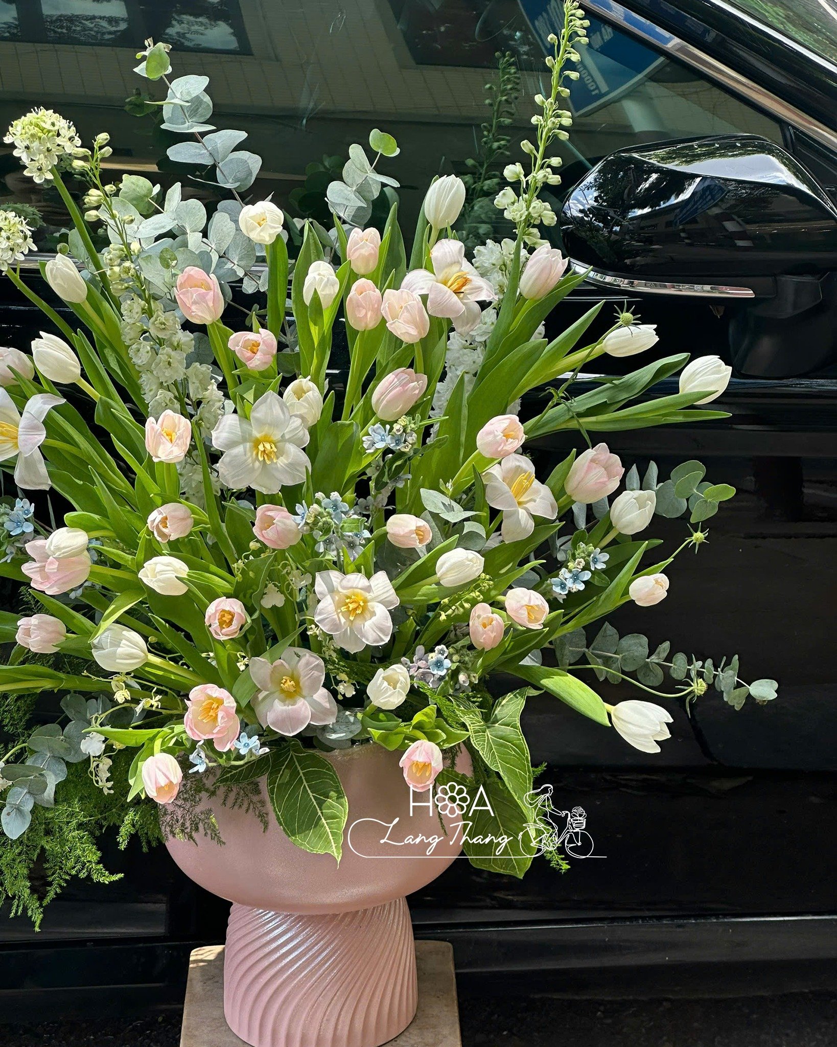 Bình hoa gồm tulip hồng, lan hồ điệp và hoa baby, cắm trang trí xe sang trọng
