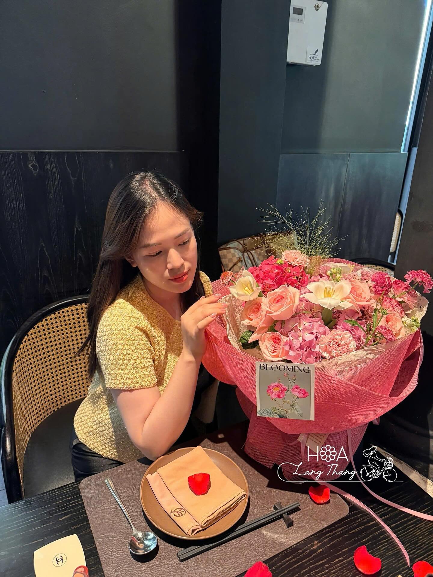 Cô gái tay cầm hoa hồng và hoa ly trong bó hoa lớn tại nhà hàng