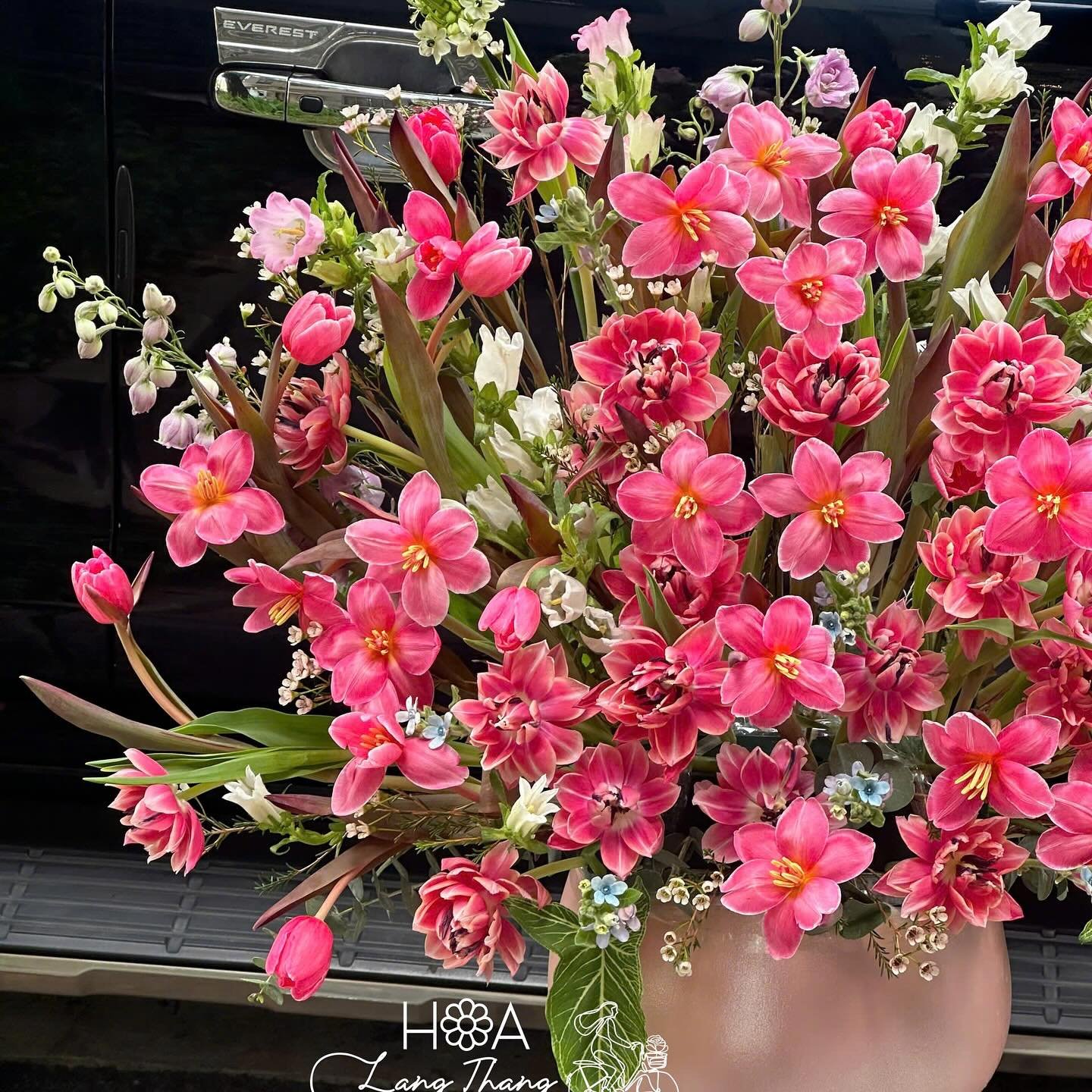 Bình hoa rực rỡ với nhiều loại hoa tươi như tulip, hồng, và mau đơn, thích hợp trang trí