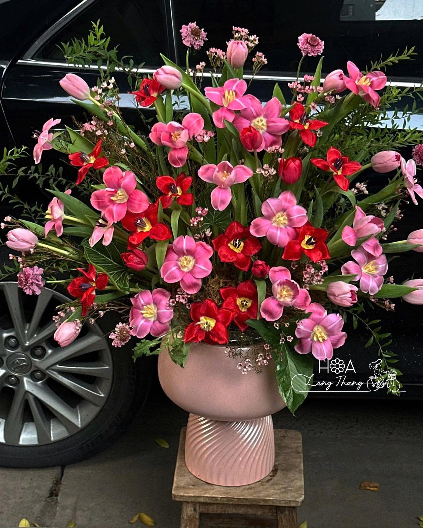 Bình hoa tươi với hoa tulip hồng và lan hồ điệp đỏ, kiểu cắm hoành tráng
