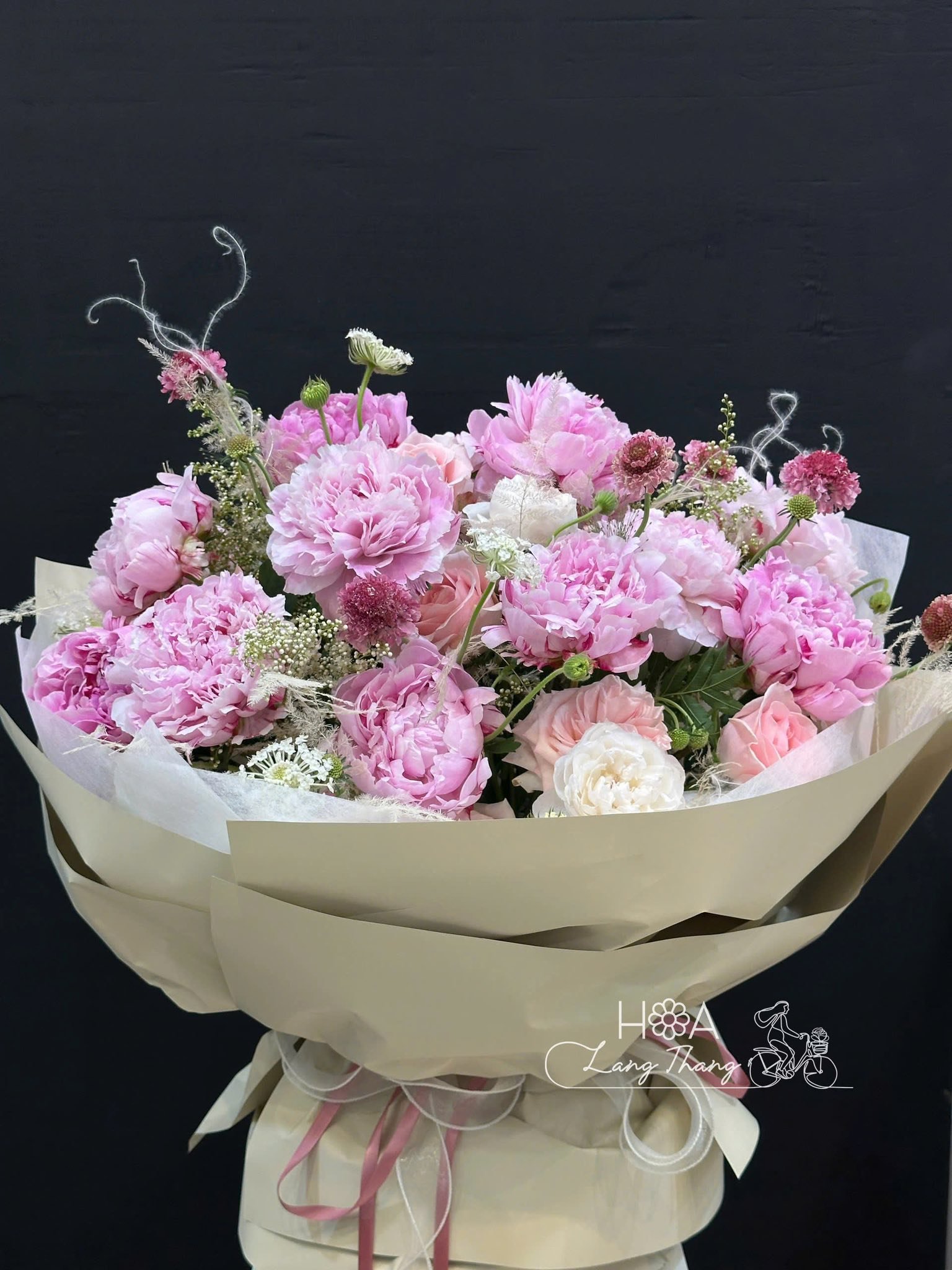 Bó hoa gồm nhiều loại hoa màu hồng tươi sáng, thích hợp cho dịp tặng. Kiểu cắm tự nhiên